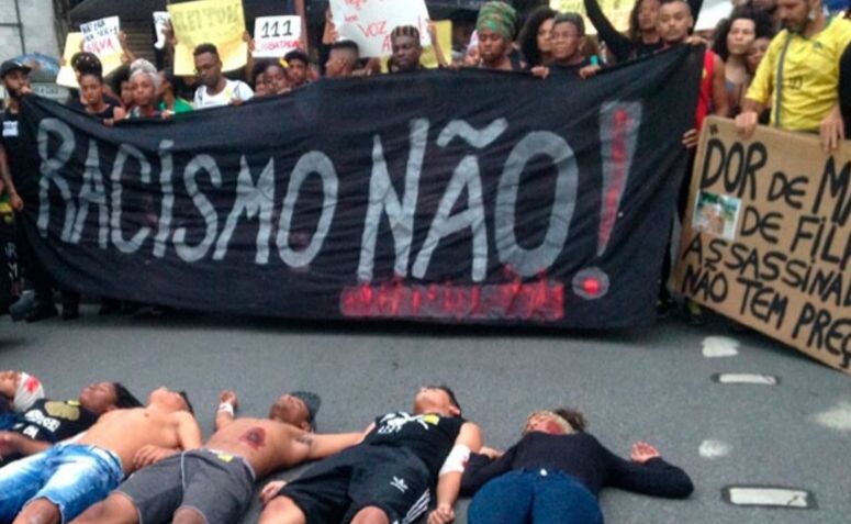 Um ato organizado pelo movimento negro, segurando uma faixa escrito "racismo não!"